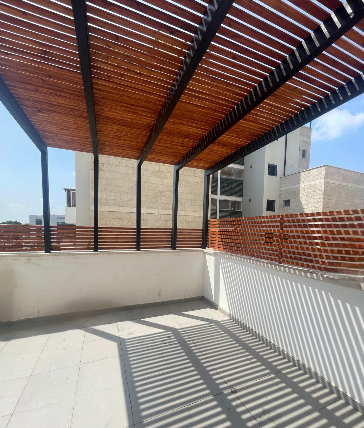 פרגולה מודרנית בצבע חום כהה עם דק עץ מותאם ותאורה נסתרת בתקרה